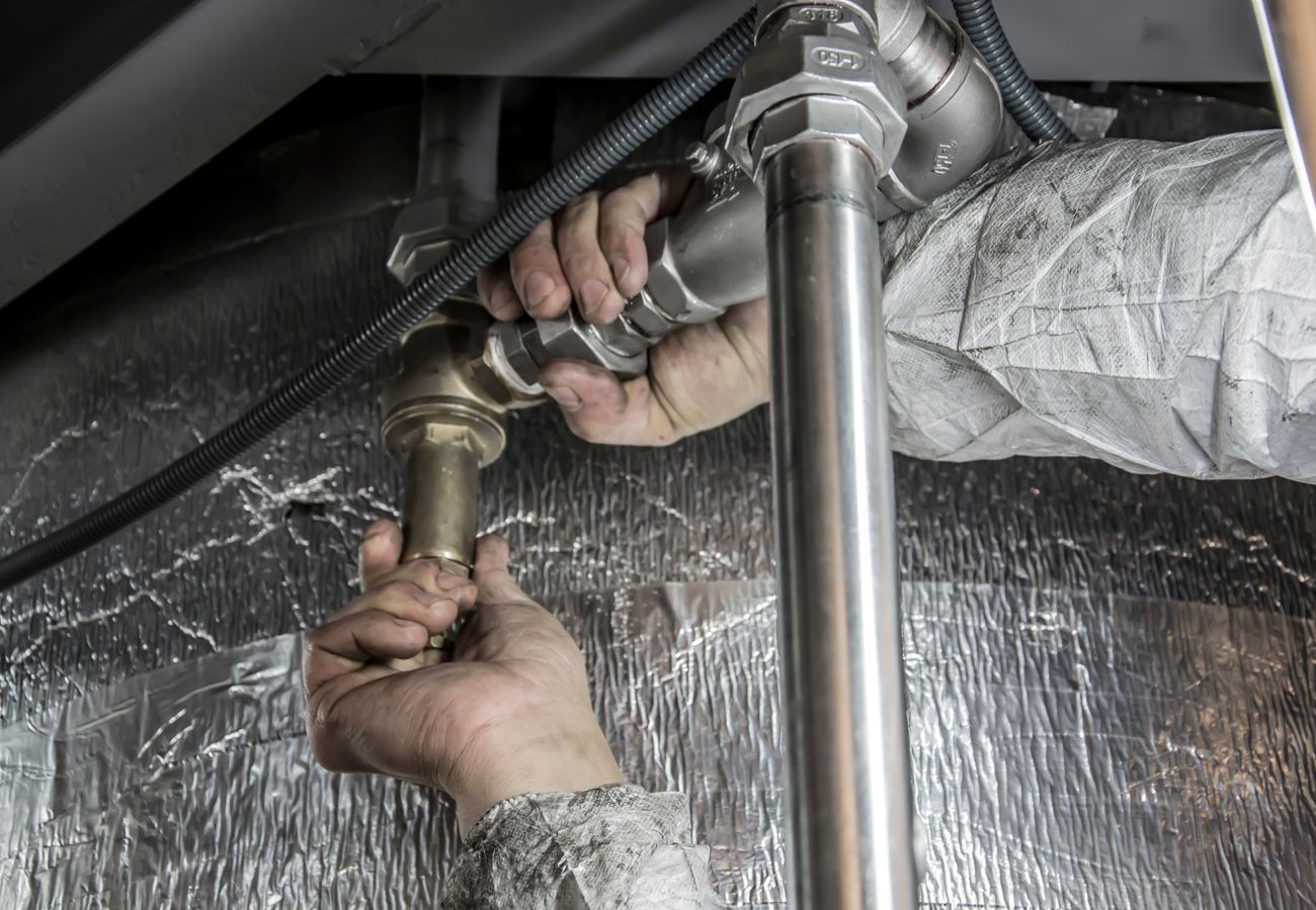 Kent’s Plumbing technician hand-tightening steel pipe fittings on a service call